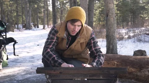 Man building fire in firepit in snowy forest Stock Footage 221033084