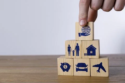 Man building pyramid of cubes with different icons on wooden table against li Fotos de archivo