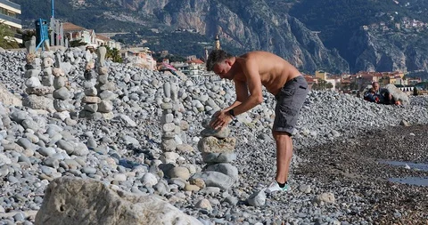 Man Building Stone Stacks On Pebble Beach Stock Footage 122162914