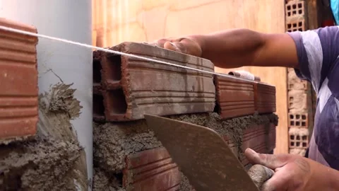 Man builds a wall with bricks and mixes cement with sand. Stock Footage 153449444