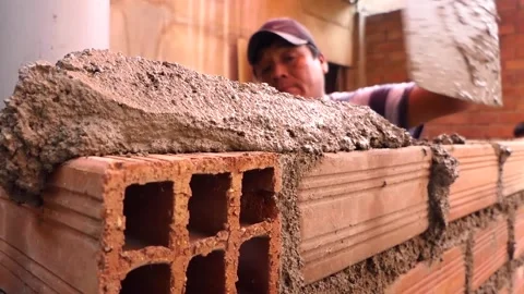 The man builds a wall with bricks and mixes cement with sand. Stock Footage 153450075