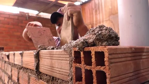 The man builds a wall with bricks and mixes cement with sand. Stock Footage 153451936