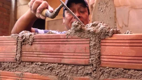 The man builds a wall with bricks and mixes cement with sand. Video stock 153452147