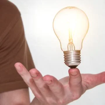 Man with bulb balancing on finger Stock Photos