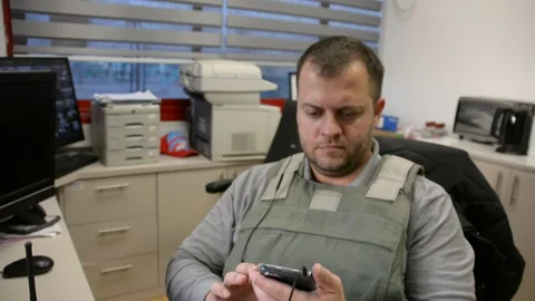 Man in bulletproof vest in security room speaks phone Video stock 172365164
