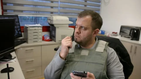 Man in bulletproof vest in security room speaks phone Video stock 172365200