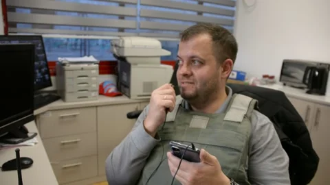Man in bulletproof vest in security room speaks phone 스톡 동영상 172365215