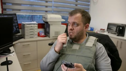 Man in bulletproof vest in security room speaks phone Video stock 172365217