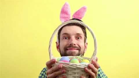 Man in bunny ears look ut behind the wicker basket with eggs happy easter Stock Footage 148226744
