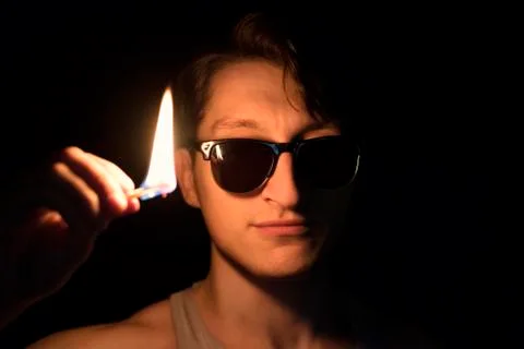 Man with a burning match in the dark. Looking into camera. Stock Photos