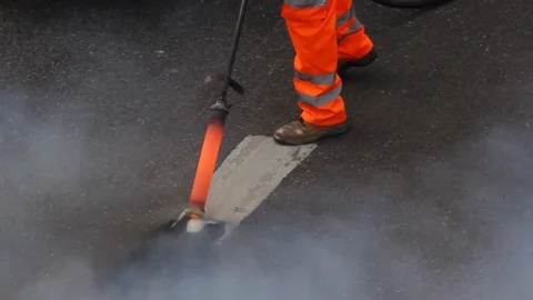 Man burning paint from road Stock Footage 95696345