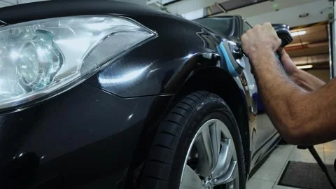 Man burnishes car shell by machine in service garage. Slow motion Stock Footage 276366473