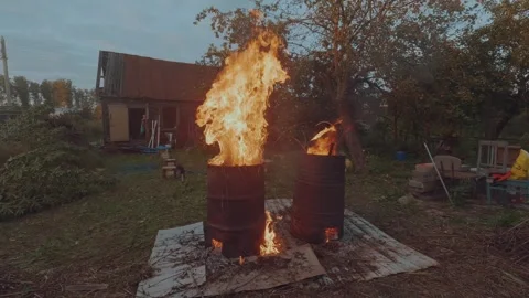 A man burns grass in an iron barrel Stock Footage 320366203