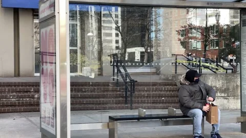 Man at bus stop twisting soda bottle waiting medical mask Covid-19 winter NYC Vídeo Stock 149334462