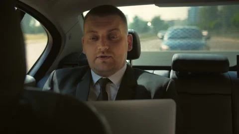 Man in a business suit rides in the back seat of a car making a video call Stock Footage 201086239