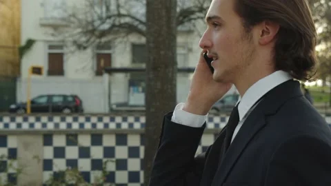 Man in a business suit is walking down the street and talking on the phone... Stock Footage 230168342