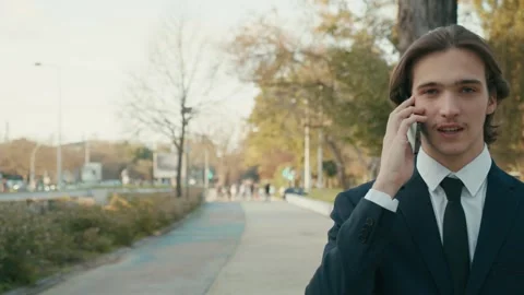 Man in a business suit is walking down the street and talking on the phone Stock Footage 302880249