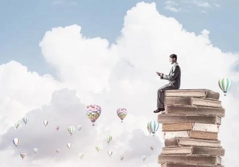 Man businessman on stack reading book and aerostats flying aroun Foto stock