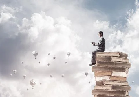 Man businessman on stack reading book and aerostats flying aroun Foto stock