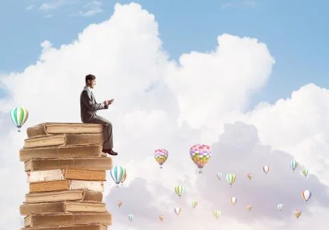 Man businessman on stack reading book and aerostats flying around 스톡 사진