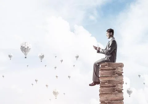 Man businessman on stack reading book and aerostats flying aroun Foto stock