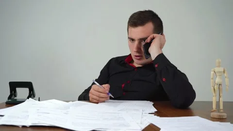 Man businessman talking on the phone while sitting at the table in the office Stock Footage 144437583