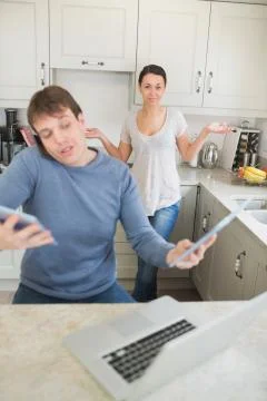Man busy with technology while his wife wondering why Stock Photos