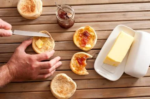 Man buttering a crumpet for breakfast Stock Photos