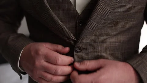 A man buttoned a brown suit jacket. 動画素材 303423196
