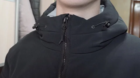 Man buttoning up black hooded jacket Stock Footage 331355274