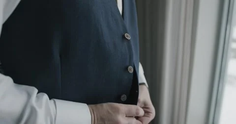 Man buttoning black vest in front of window Video stock 172610861