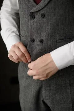 Man buttoning grey textured double-breasted vest close up, elegant groom wedding Фото