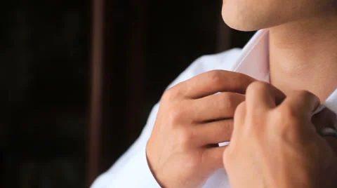 Man buttoning his shirt in front of a window Stock Footage 63535449