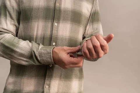 Man buttoning shirt cuff in closeup studio scene. Stock-Fotos