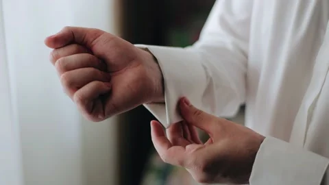 The man is buttoning the sleeve of a white shirt Stock Footage 220723091