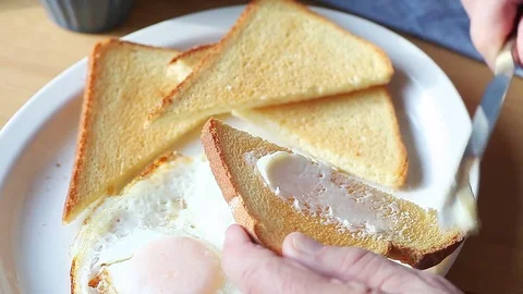 Man butttering toast at breakfast Stock Footage 75427105