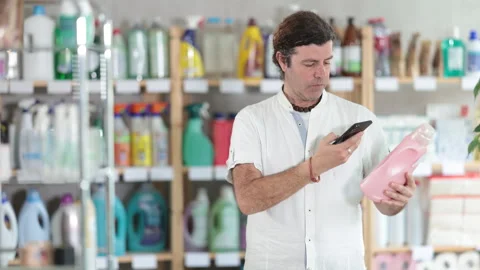 Man buyer scans qr code on liquid laundry powder label Stock Footage 320926782