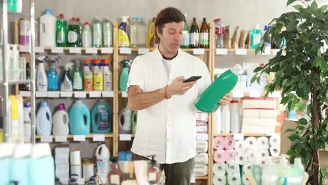Man buyer scans qr code on liquid laundry powder label Stock Footage 332735661