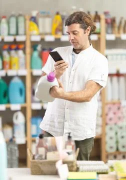 Man buyer scans qr code on liquid laundry powder label Stock Photos