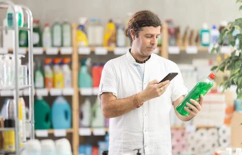 Man buyer scans qr code on dishwashing soap label Stock Photos