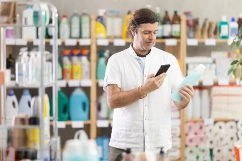 Man buyer scans qr code on shower gel label Stock Photos