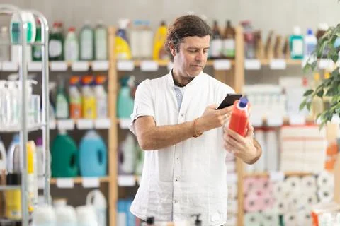 Man buyer scans qr code on sewer cleaner liquid label Stock Photos