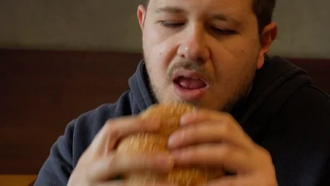  man bytes a big burger. Portrait of  man eating burger Video stock 74689096
