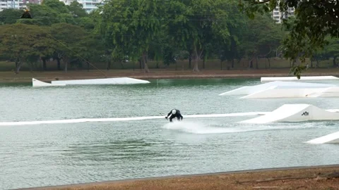 Man Cable Skiing and Wakeboarding at a Tropical Water Park in Singapore Stockbeeldmateriaal 328699052
