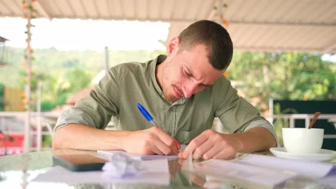 A man in a cafe diligently takes notes with a pen in a notebook. Video stock 231336155
