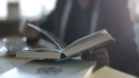 A man in a cafe drinking coffee and reading a book. Slow motion Stock Footage 43158869