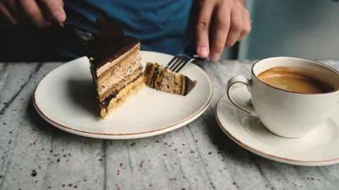 A man in a cafe drinks coffee and cuts a piece of coffee cake Stock Footage 196286593