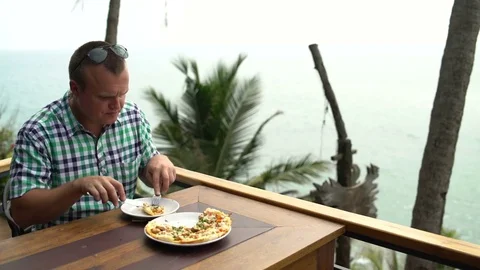 A man in a cafe is eating pizza with a fork and knife Video stock 74893264