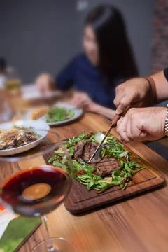 Man in the cafe eats beef steak with greens close-up Stock Photos
