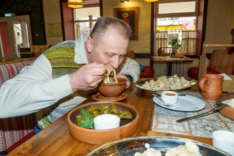 A man in a cafe eats a freshly prepared Caucasian dish. Stock Photos